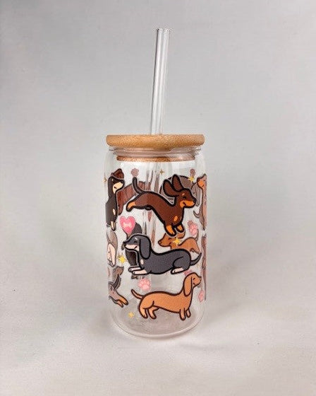 Glass tumbler with wooden lid and straw featuring illustrations of wiener dogs