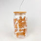 Clear tumbler with brown dachshund gingerbread illustrations and a wooden lid