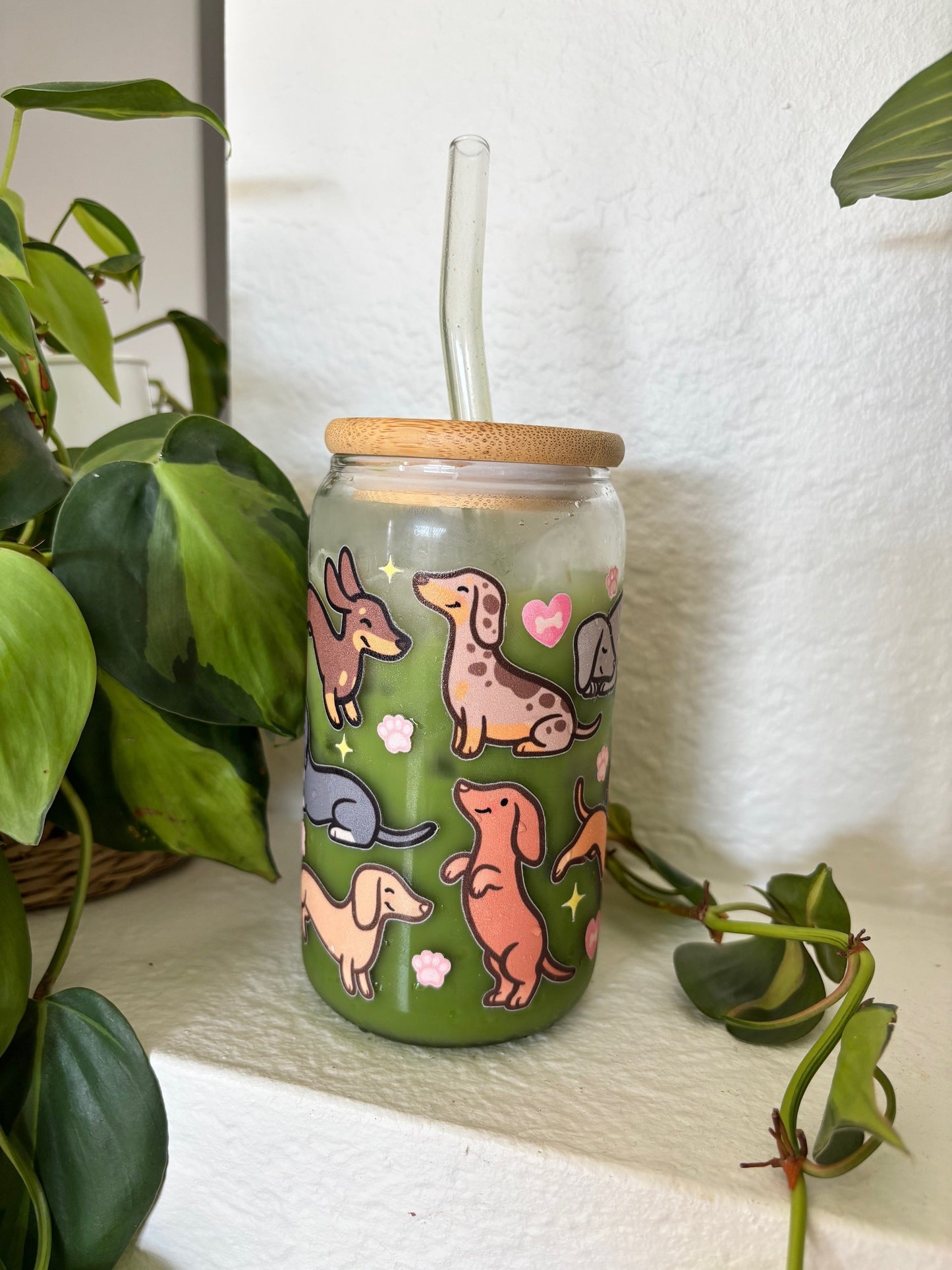 eco friendly cup with dachshund illustrations on a white surface with plants.